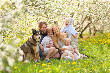 Happy Family and Pet Dog Relaxing in Flower Orchard