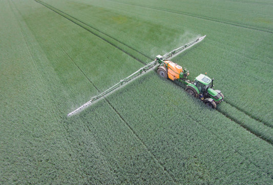 Pflanzenschutz im Getreide, Schlepper mit Feldspritze - Luftaufnahme