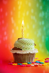 cupcake mitbrennender Kerze und buntem Hintergrund