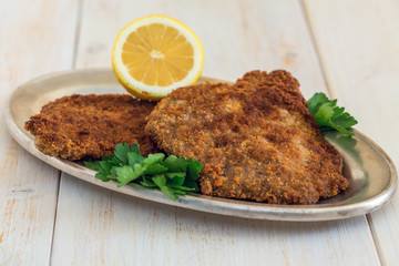 Schnitzel beef with lemon on a metal tray.