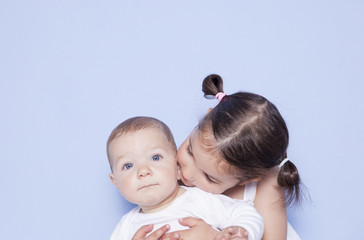 Little cute girl hugging little baby brother