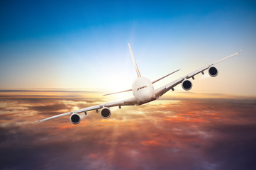 Fototapeta na wymiar Airplane flying above clouds in dramatic sunset