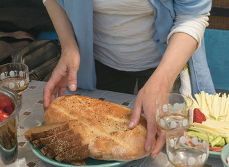 Woman hands are setting loaf on serving plate for lunch.