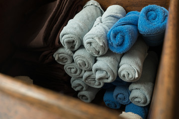 clean nice shape of light gray and blue rolled towel and brown comfort pants in the wooden box. they was prepared for welcoming guest and changing for Thai massage.