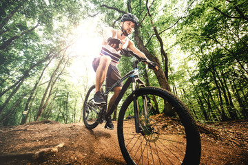 Naklejka premium cyclist with helmet riding mountain bike on rocky forest trail a