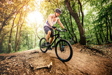 Professional mountain bike cyclist riding trail in forest