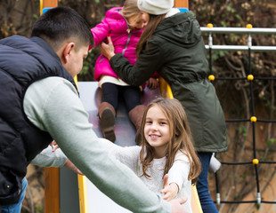 Fototapeta na wymiar Parents helping kids on slide
