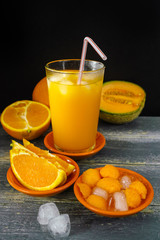 Glass with fresh ice cold pressed melon-orange juice and fresh f