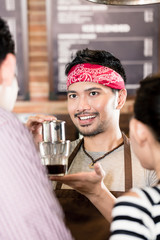 Barista showing woman how to make drip coffee in cafe