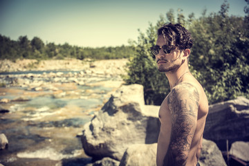 Athletic shirtless young man outdoor at river or water stream