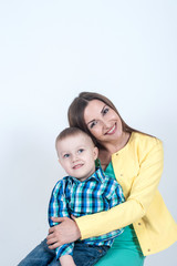 Boy in shirt sitting with mom on light background