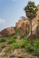 Chettinad, India - October 16, 2013: View from outside the Thirumayam fort on a corner of the fortifications. Boulders and trees in foreground.