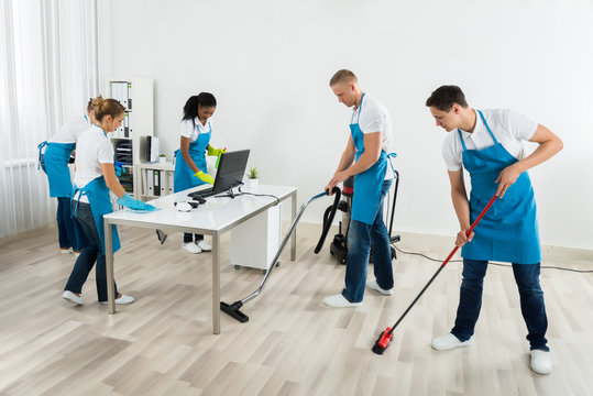 Group Of Janitors Cleaning The Office