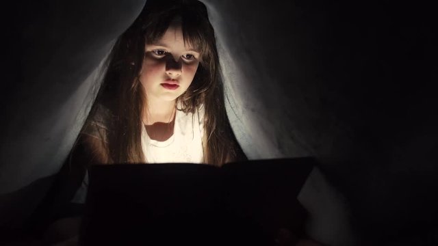 Girl use tablet pc under blanket