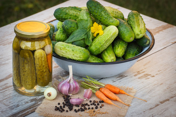 Cucumbers in metal bowl, vegetables and spices for pickling and jar pickled cucumbers