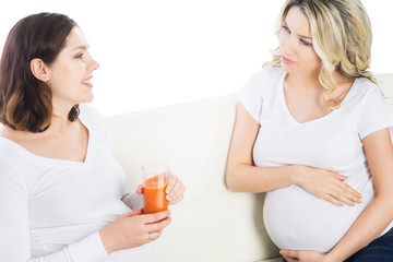 Two expectant mothers staying healthy with fruits and fresh juic