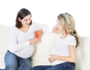 Two expectant mothers staying healthy with fruits and fresh juic