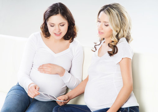 Two young beautiful pregnant women watching ultrasound scans