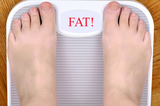 Barefoot Person Standing On The Weight Scale. The Scale Shows FAT!