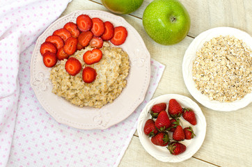 Oatmeal with strawberries and apples on the table. The view from