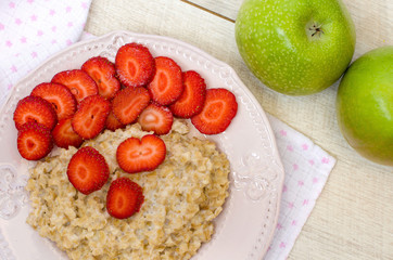 Oatmeal with strawberries and apples on the table. The view from