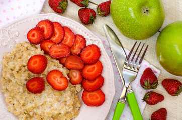 Oatmeal with strawberries and apples on the table. The view from