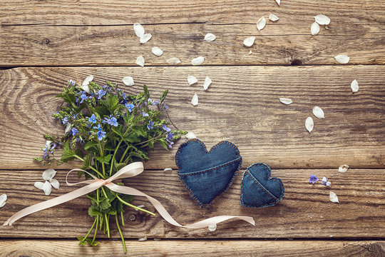 Bouquet of blue wild flowers and denim heart on a background of old wooden planks. Place for text. Top view.