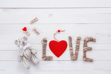 A small teddy bear, clothespins and cardboard letters on a white