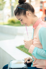Young woman with tablet and iced latte in town