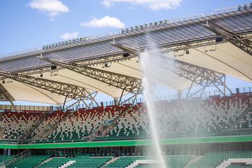 Watering grass on big sport stadium - obrazy, fototapety, plakaty