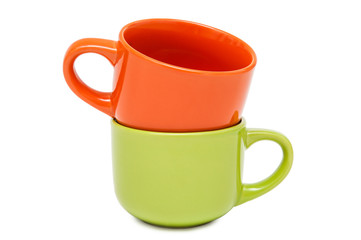Two colorful ceramic cups stand on each other on a white backgro