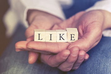 Hands holding Like message formed with wooden blocks