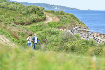 Senior couple walking on hiking track by the coast