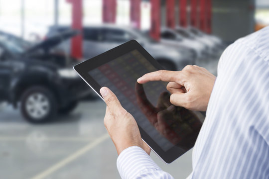 Closeup of a man checking the car on touchscreen tablet in a garage