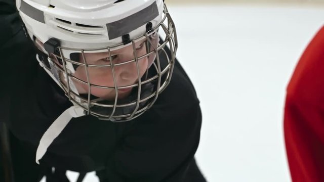 Close up of little hockey player in helmet standing face to face with his opponent and looking at him