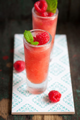 Homemade summer cold raspberry cocktail with crushed iced and alcohol in glasses on a vintage background, closeup.