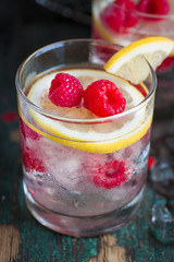 Homemade summer cold raspberry lemon cocktail with sparkling water and crushed iced in glasses on a vintage background, closeup