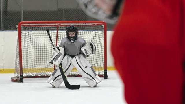 Hockey goaltender in protective uniform catching the puck and preventing opposing team from scoring