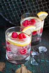 Homemade summer cold raspberry lemon cocktail with sparkling water and crushed iced in glasses on a vintage background, closeup