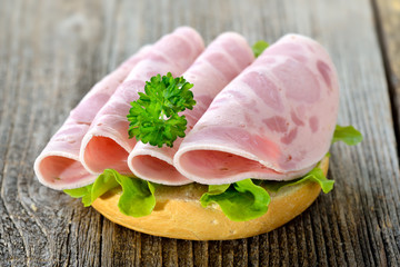 Garniertes Brötchen mit Schinkenwurst, Salatblatt und Petersilie - Open faced sandwich with sliced...