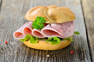 Garniertes Brötchen mit Schinkenwurst, Salatblatt und Petersilie - Roll with sliced ham sausage and lettuce leaf