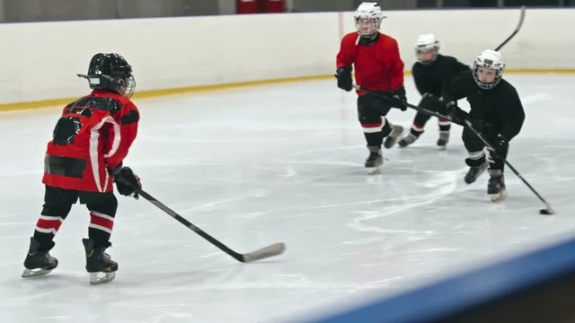 Bunch of kids in professional uniform playing hockey on skating rink