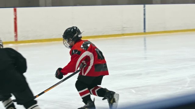 Talented little hockey player pushing the puck into the net of opposing team in slow motion