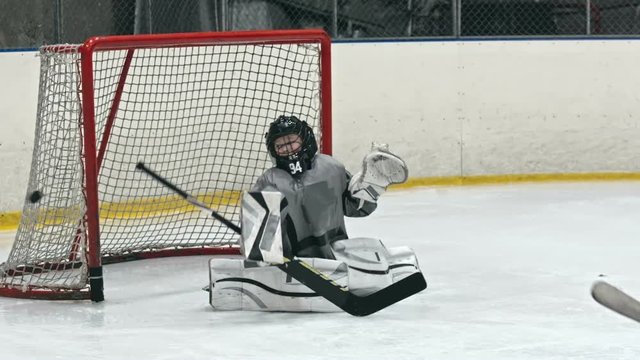 Child playing the position of goalie on an ice hockey team and protecting net from opposing team