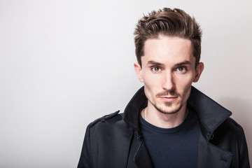 Fototapeta premium Elegant young handsome man in long stylish dark blue coat. Studio fashion portrait.
