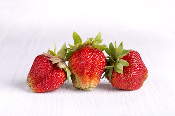 Three ripe red strawberries on white wooden blackboard