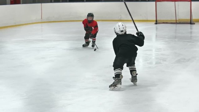 Children in red and black uniform playing professional ice hockey in slow motion