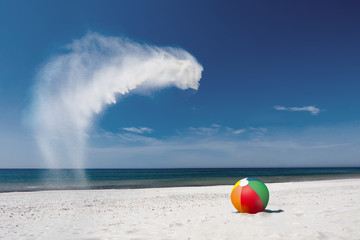 Beach ball on the white beach with flying sand