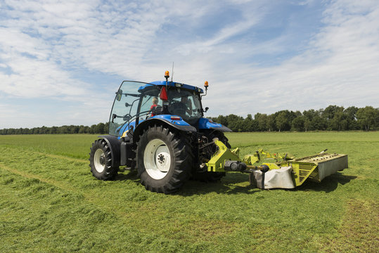 pasture mowing with blue tractor and mower