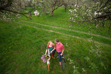 Happy young couple with bicycles looking at each other against the background of fresh green grass. Man and woman together enjoying romantic holidays. View from above